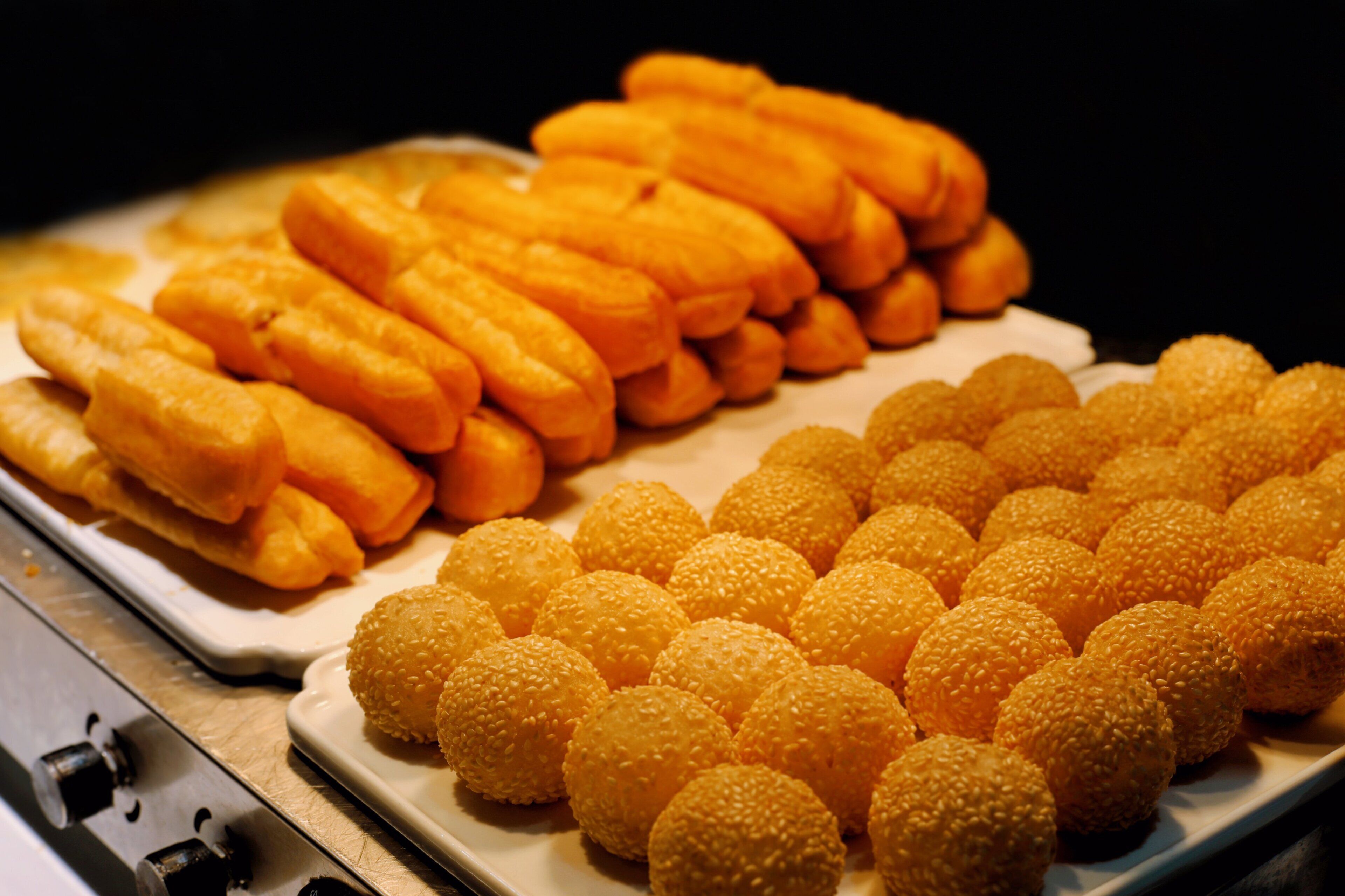 Un plateau contenant divers aliments, notamment des gressins et des boules recouvertes de graines de sésame.