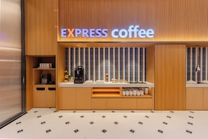 Interior de una cafetería con un mostrador de madera, una máquina de café y un letrero que dice 'EXPRESS coffee'.