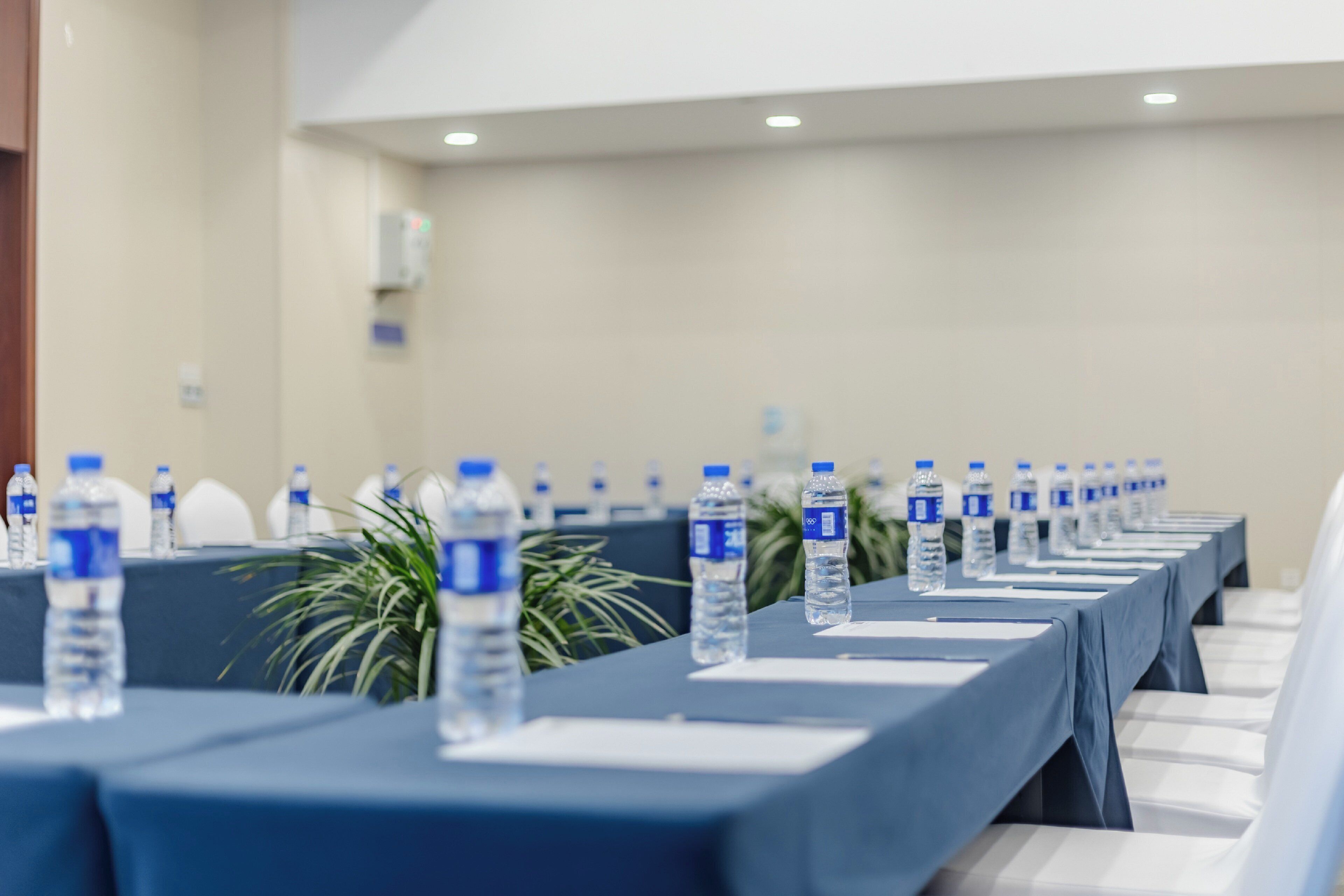 A conference room with rows of tables, each with a water bottle.