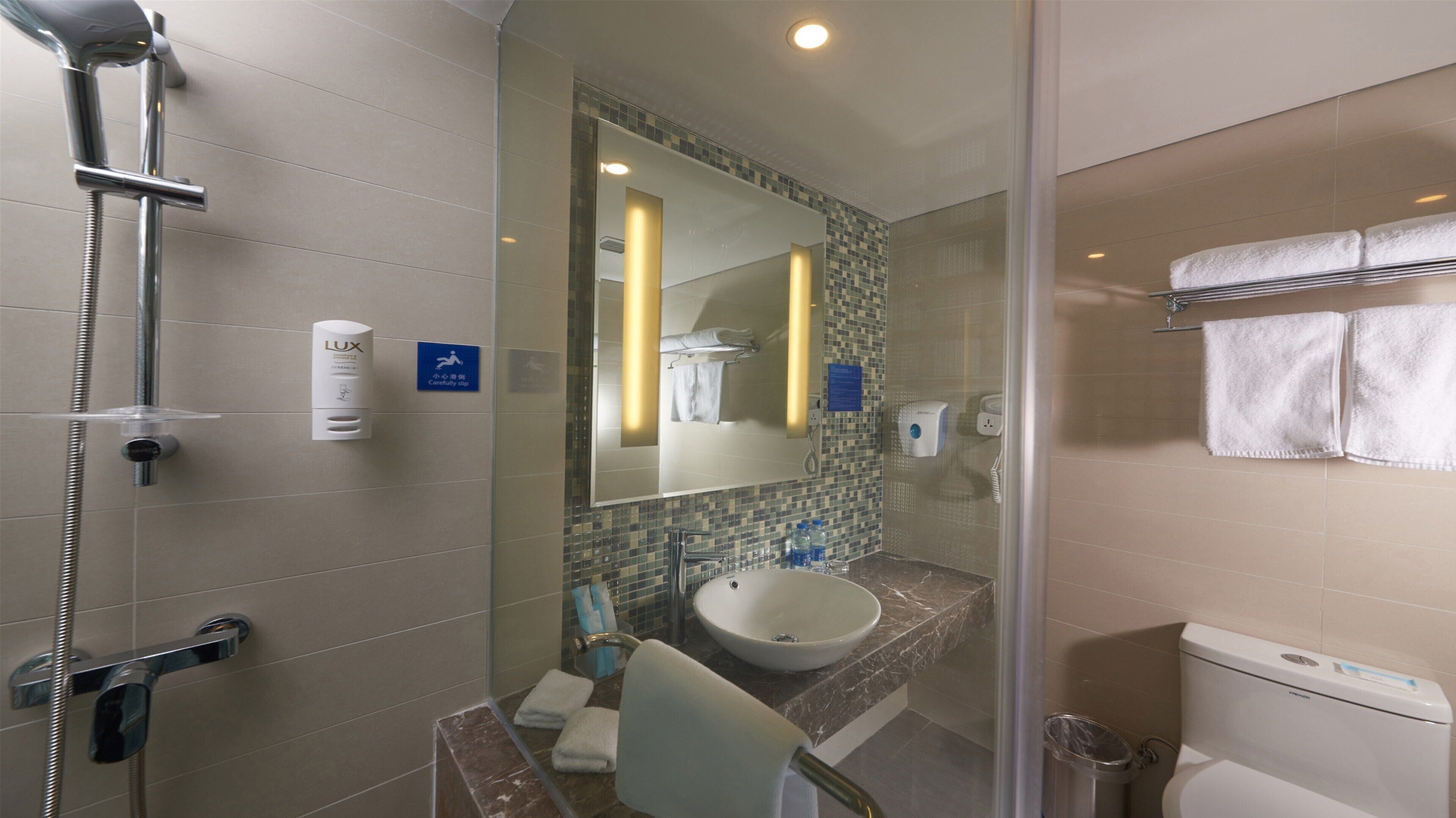 A modern bathroom with a glass-enclosed shower, a sink with a marble countertop, and a toilet.