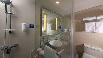 A modern bathroom with a glass-enclosed shower, a sink with a marble countertop, and a toilet.