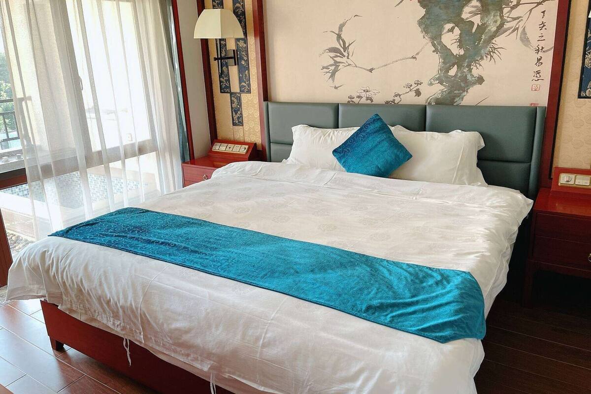 A neatly made bed with a blue accent pillow, a white bedspread, and a blue throw blanket.
