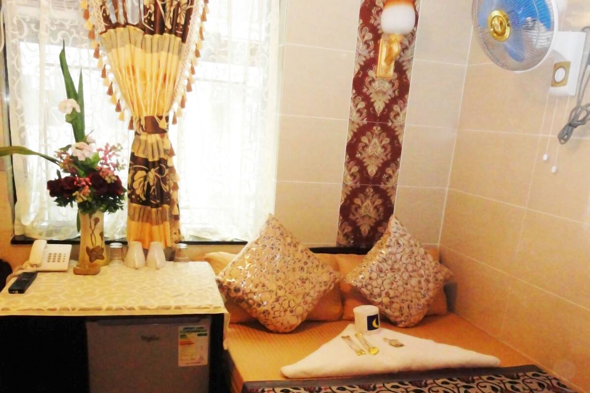 A bathroom with a toilet, a sink, a mirror, a fan, and decorative pillows.
