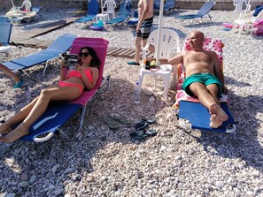 On the beach, sun-loungers, beach umbrellas, motor boating