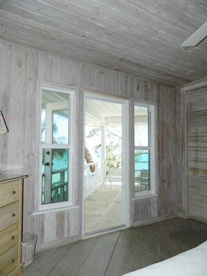 A room with wooden walls and a large sliding glass door leading to an outdoor patio.