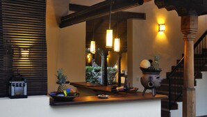 Una zona de bar con mostrador de madera, un espejo y objetos decorativos, incluyendo una piña y una maceta.