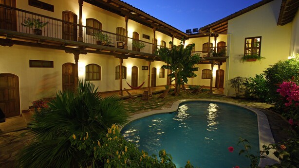 Un patio con piscina, rodeado de edificios con balcones y macetas.