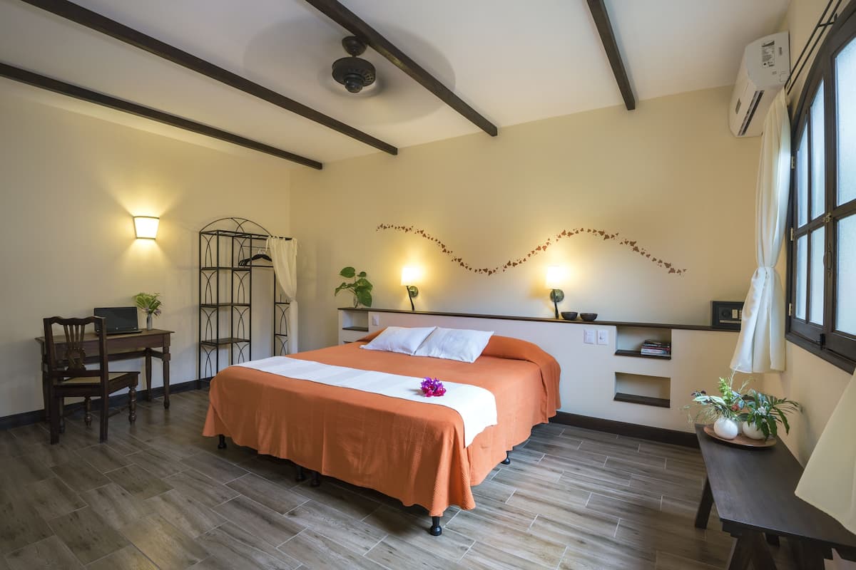 Ein Hotelzimmer mit Bett, Schreibtisch, Stuhl und Topfpflanzen.