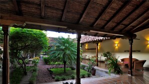 Un patio cubierto con suelo de baldosas, columnas de madera y plantas en macetas.