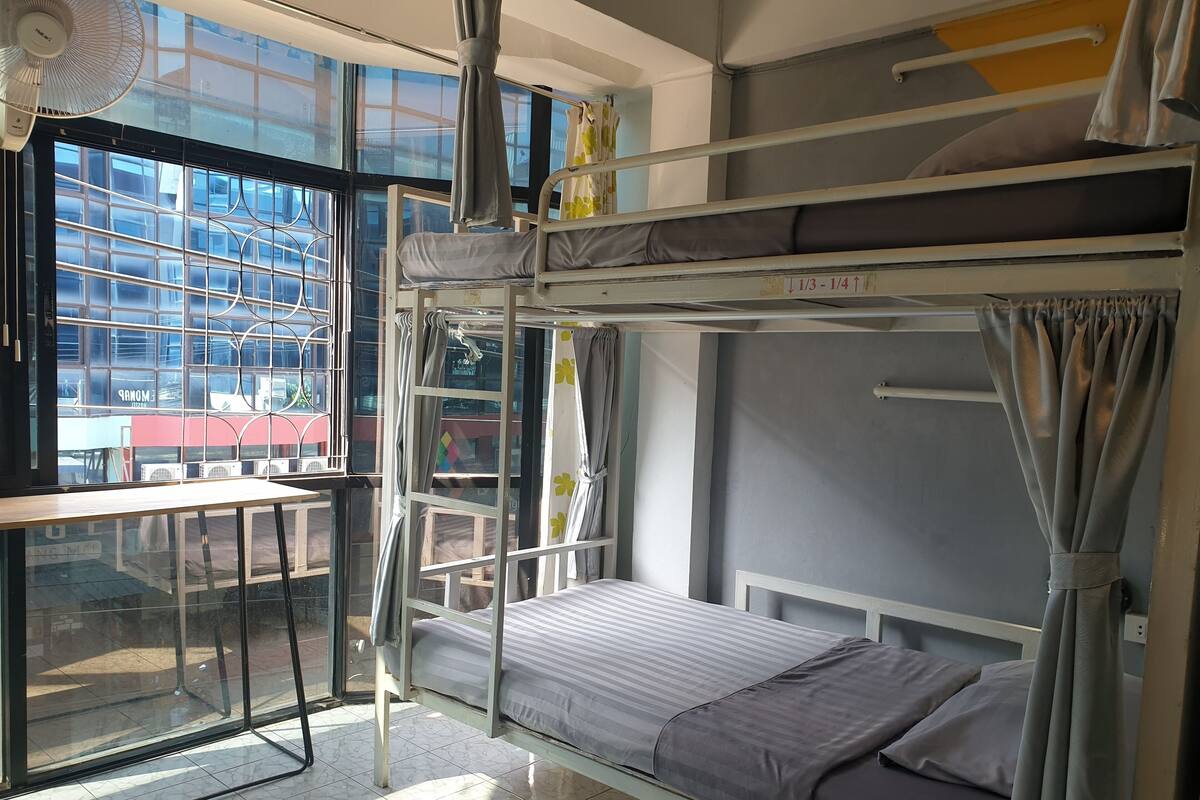 Dormitorio con literas, ventana, escritorio y ventilador.
