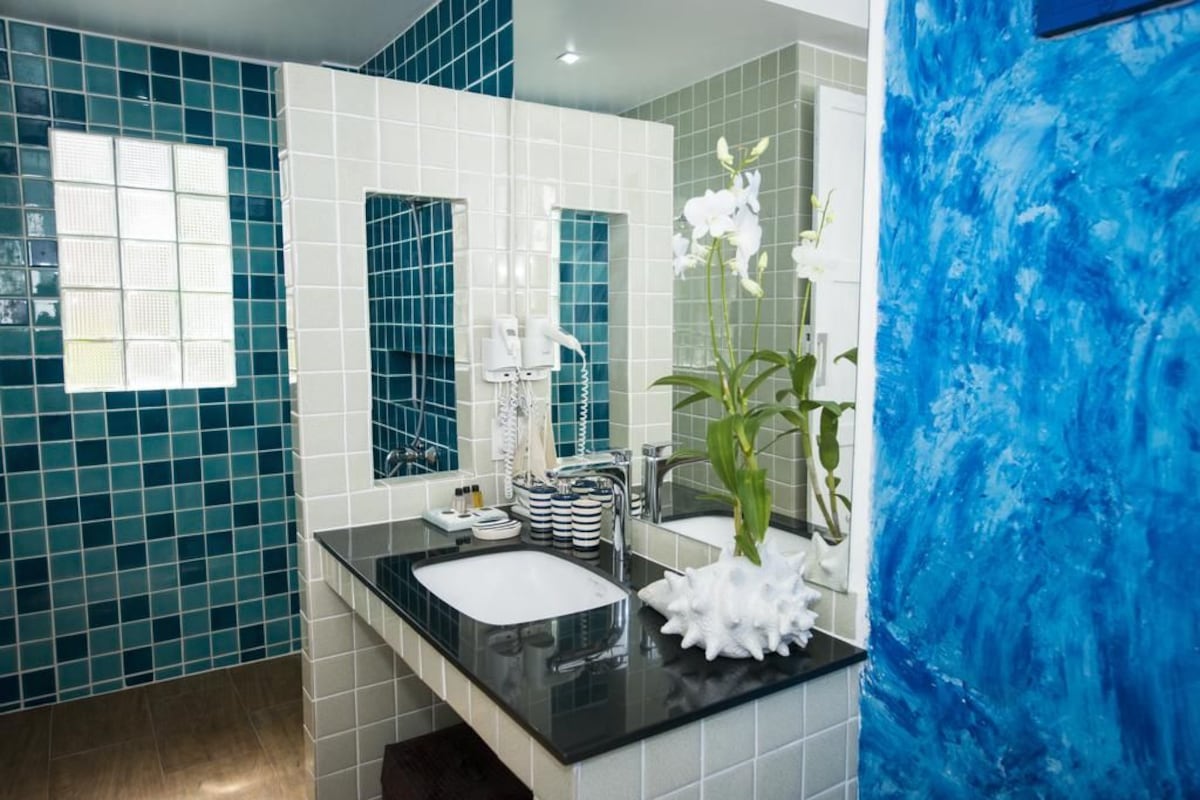 Une salle de bain moderne avec un plan de toilette noir, un lavabo blanc et un miroir.