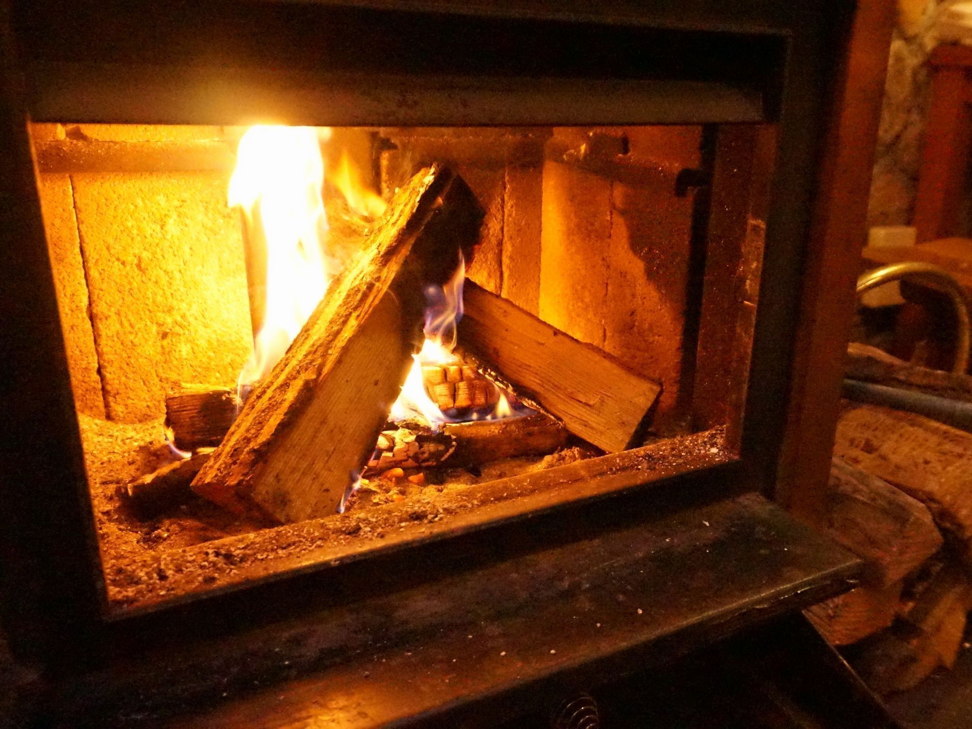 A wood-burning stove with logs and flames.
