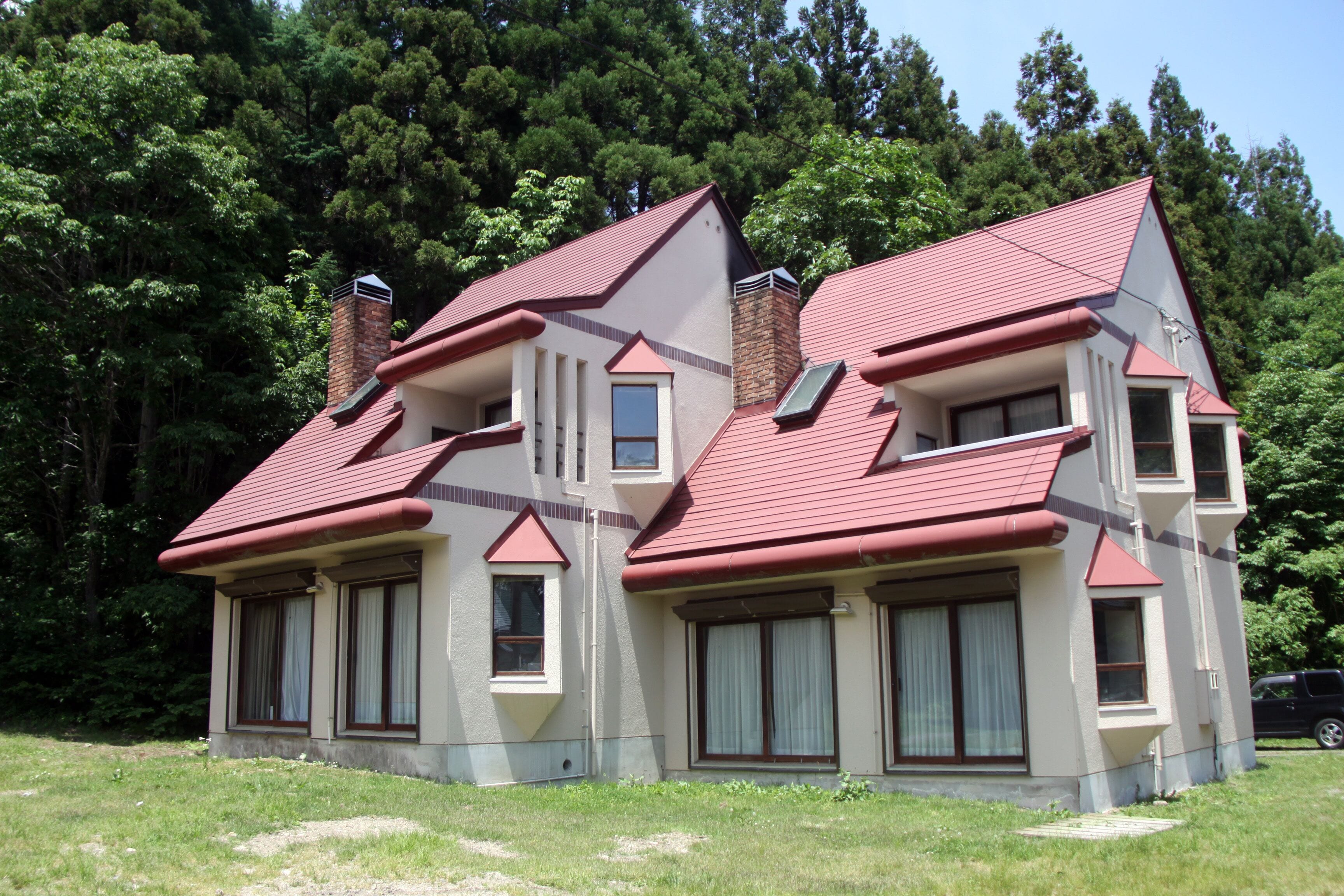 A two-story house with a red roof, multiple windows, and a chimney.