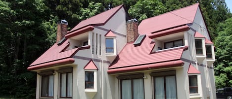 Una casa de dos pisos con techo rojo, varias ventanas y una chimenea.