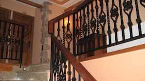 A staircase with a wooden handrail and black wrought iron balusters. - Centro de Turismo Rural Lajafriz (Fonfria)