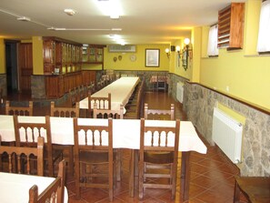 A dining hall with long tables and wooden chairs, stone walls, and a tiled floor. - Centro de Turismo Rural Lajafriz (Fonfria)