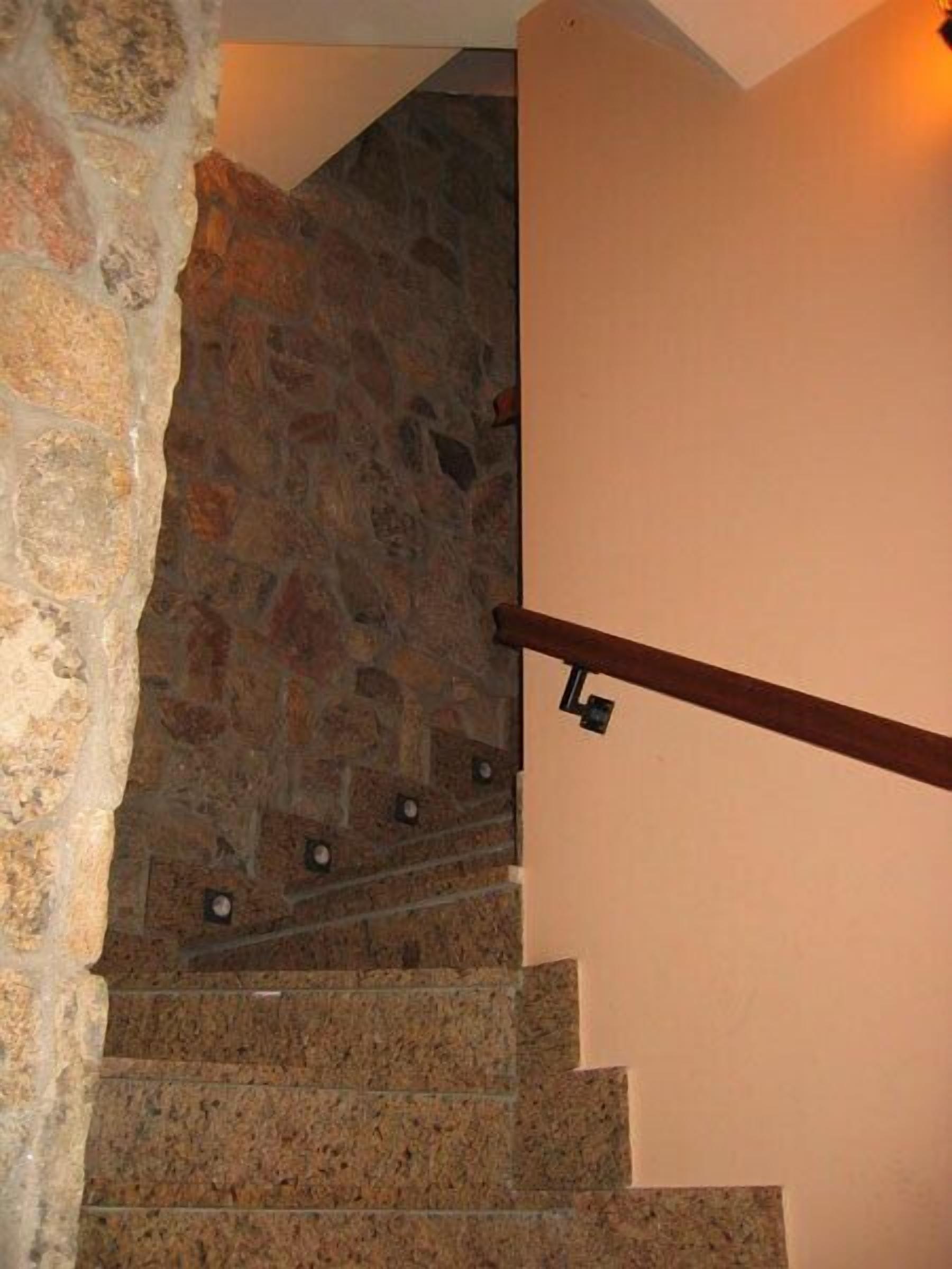 Una escalera con paredes de piedra y barandal de madera.