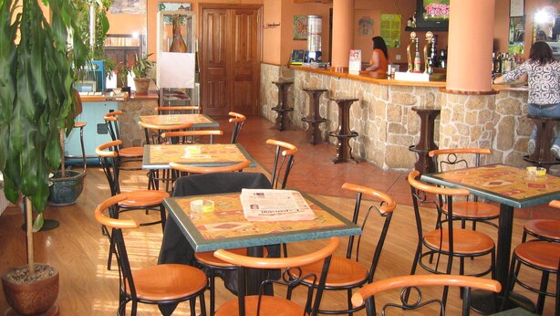 A restaurant interior with multiple tables and chairs, a bar area, and a wooden ceiling. - Centro de Turismo Rural Lajafriz (Fonfria)