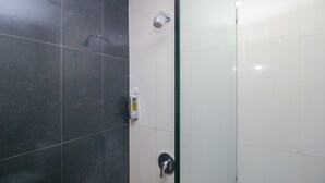 A bathroom with a shower, a hand dryer, and a soap dispenser.