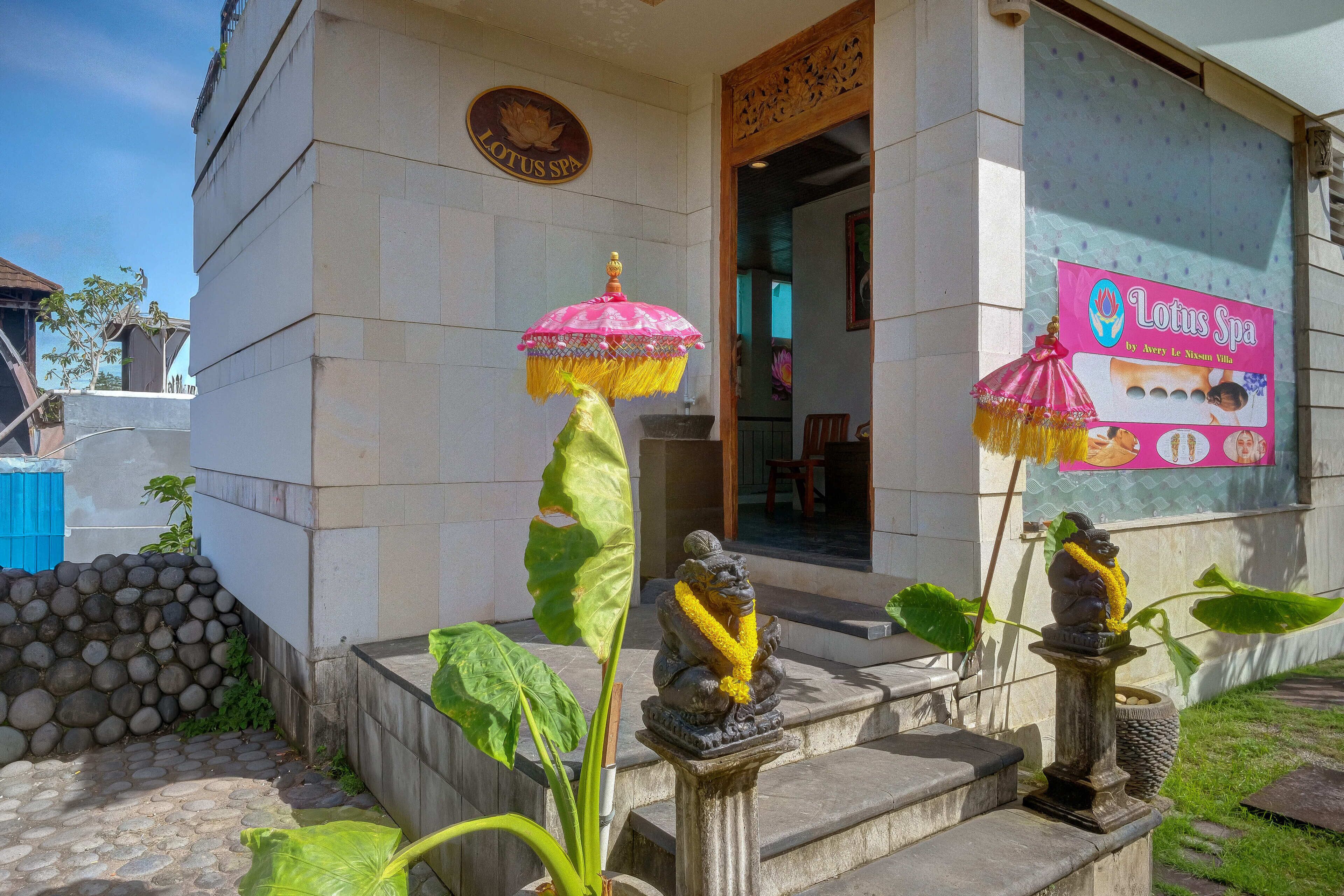 Un edificio con un letrero que indica Lotus Spa, escalones de piedra y una estatua de una figura sentada con una guirnalda.