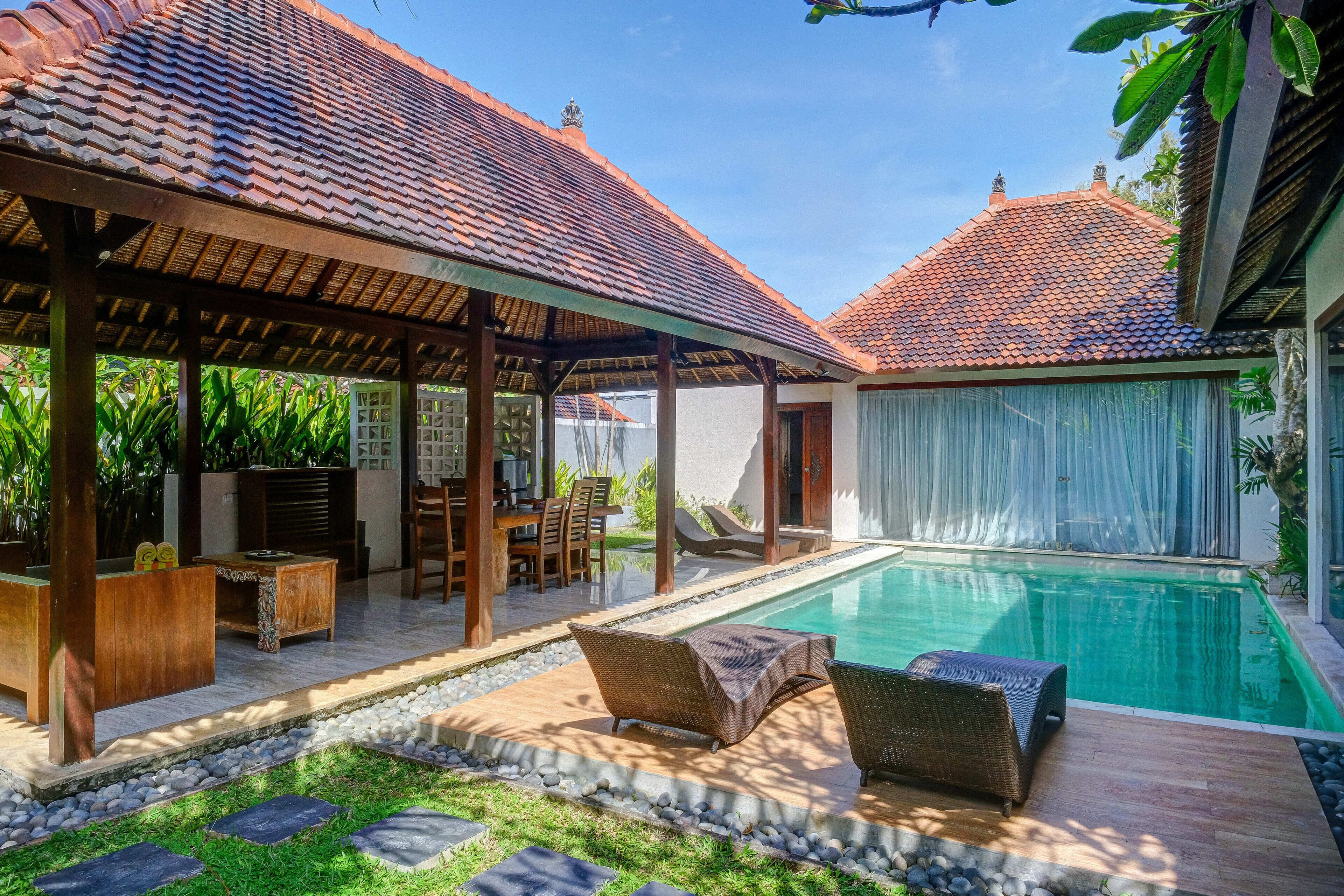 A poolside area with a covered seating area, a pool, and a garden.
