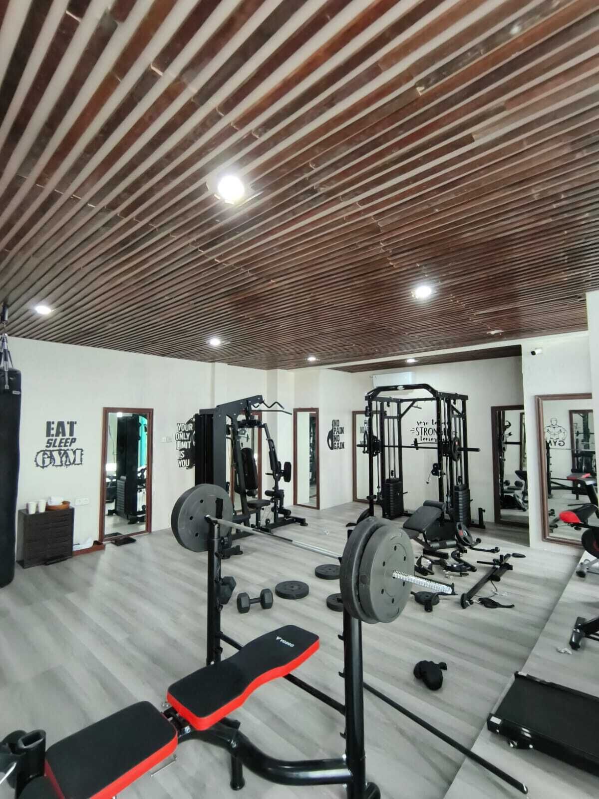 A gym with weightlifting equipment, benches, and motivational wall quotes.