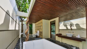 Un baño moderno con una bañera grande, techo de madera y pared de piedra.
