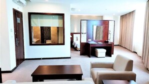 Une chambre d’hôtel moderne dotée d’un espace salon, d’un bureau, d’un canapé et d’une grande fenêtre.