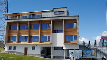 Ein modernes Gebäude mit mehreren Etagen, großen Fenstern und einer Holzfassade.