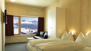 A bedroom with a large bed, a sofa, and a window with a mountain view. - Venet Gipfelhütte (Zams)