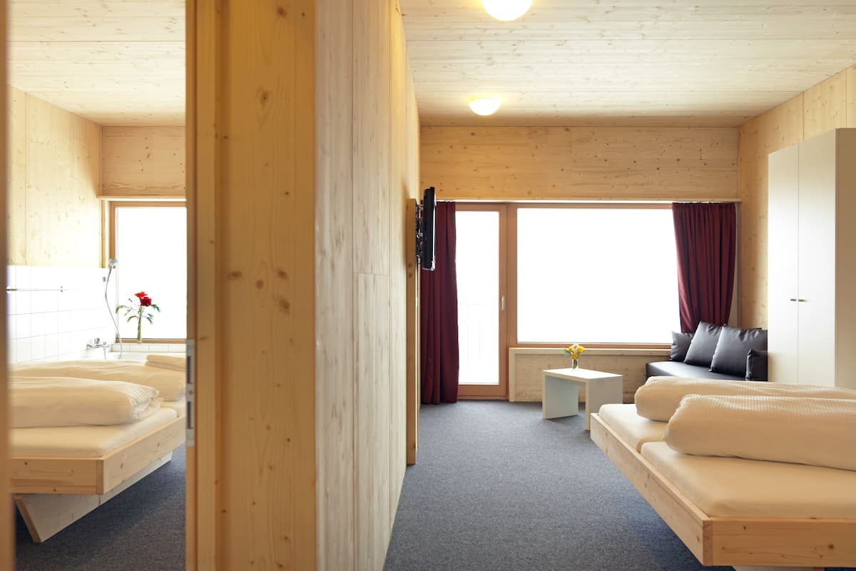 A hotel room with two beds, a sofa, a small table, and a TV.