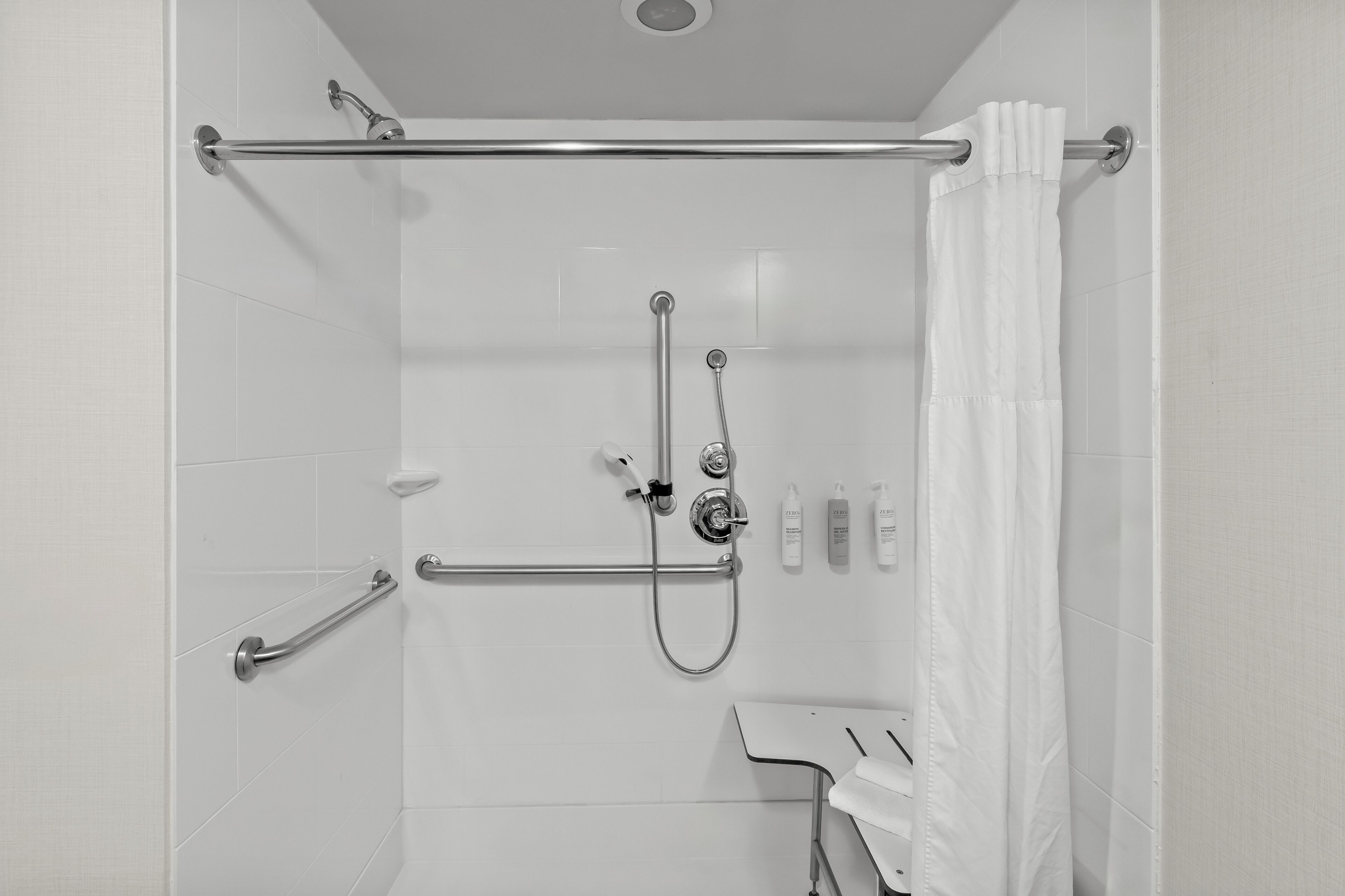 Une douche équipée d’une barre d’appui, d’un pommeau de douche amovible et d’un porte-serviettes.