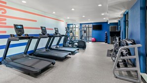 Ein Fitnessstudio mit Laufbändern, Kraftgeräten und einem roten Trainingsball.