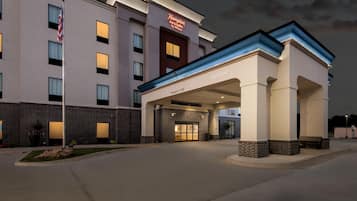 Edificio de Hampton Inn & Suites by Hilton con entrada despejada, fachada de ladrillo y un letrero acogedor.