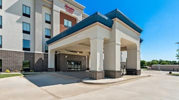 A hotel entrance with a covered walkway, columns, and a 'Welcome' sign.