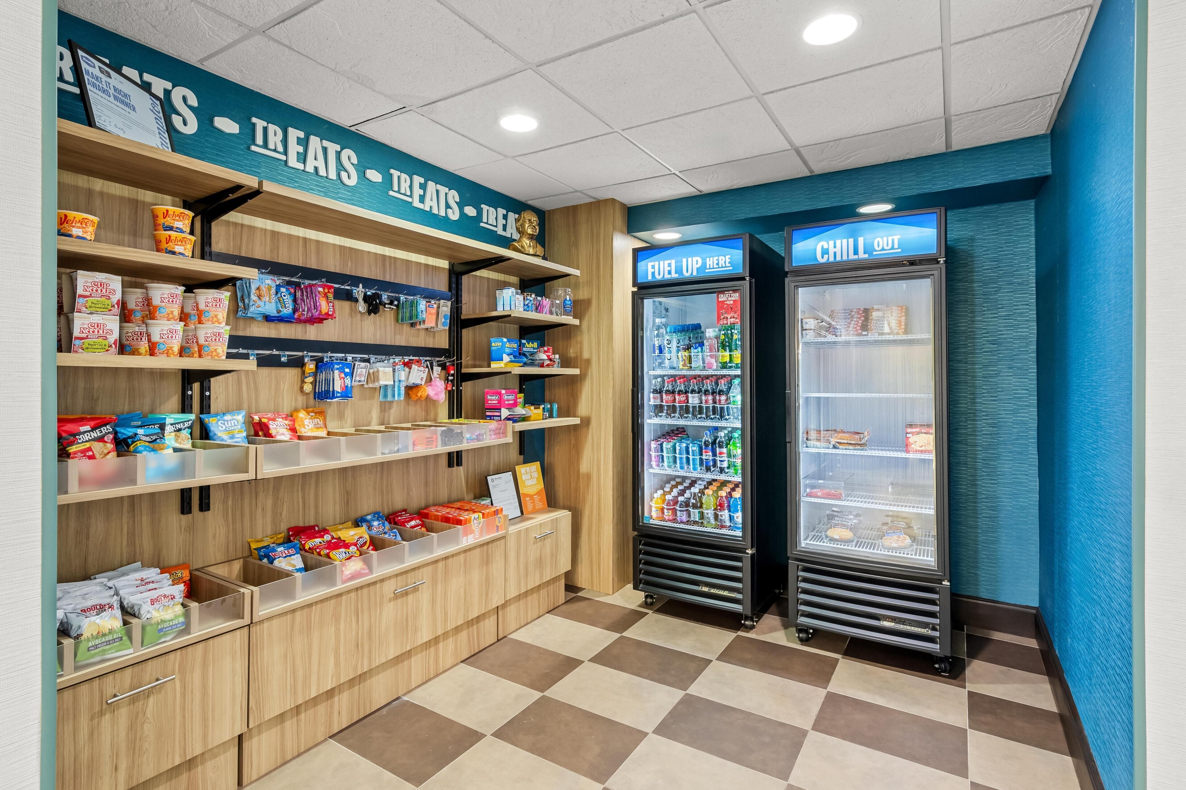 A snack and beverage area with shelves stocked with snacks and a refrigerated display case.