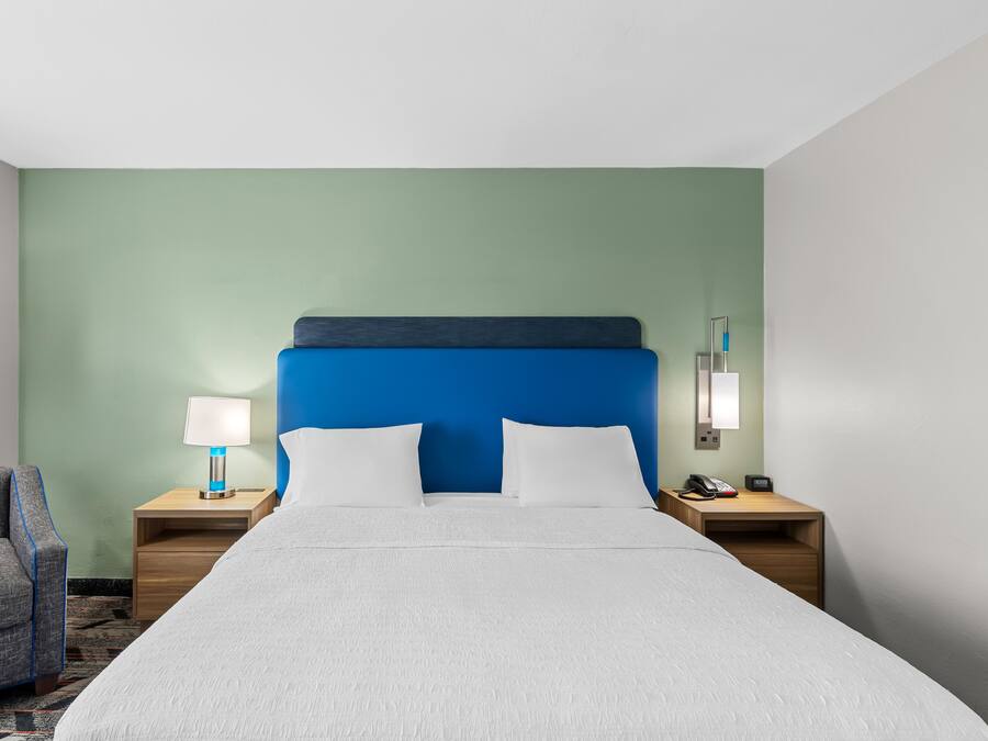 Een hotelkamer met een bed, twee nachtkastjes, een stoel en een lamp.