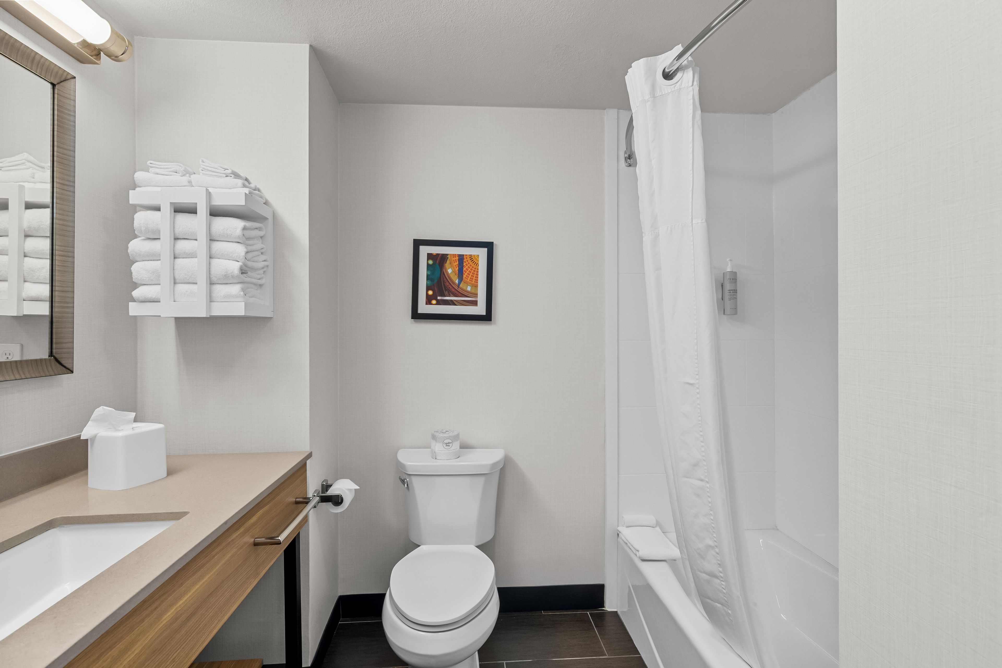 Ein Badezimmer mit Toilette, Waschbecken, Handtuchhalter und einem gerahmten Bild an der Wand.