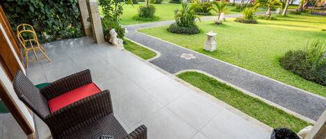 A patio area with wicker furniture and a view of a well-maintained garden and beach.