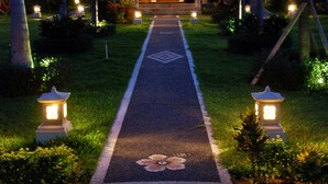 A pathway leading to a building with a tiled roof, surrounded by palm trees and lit by lanterns. - Bali Dive Resort and Spa (Tulamben)