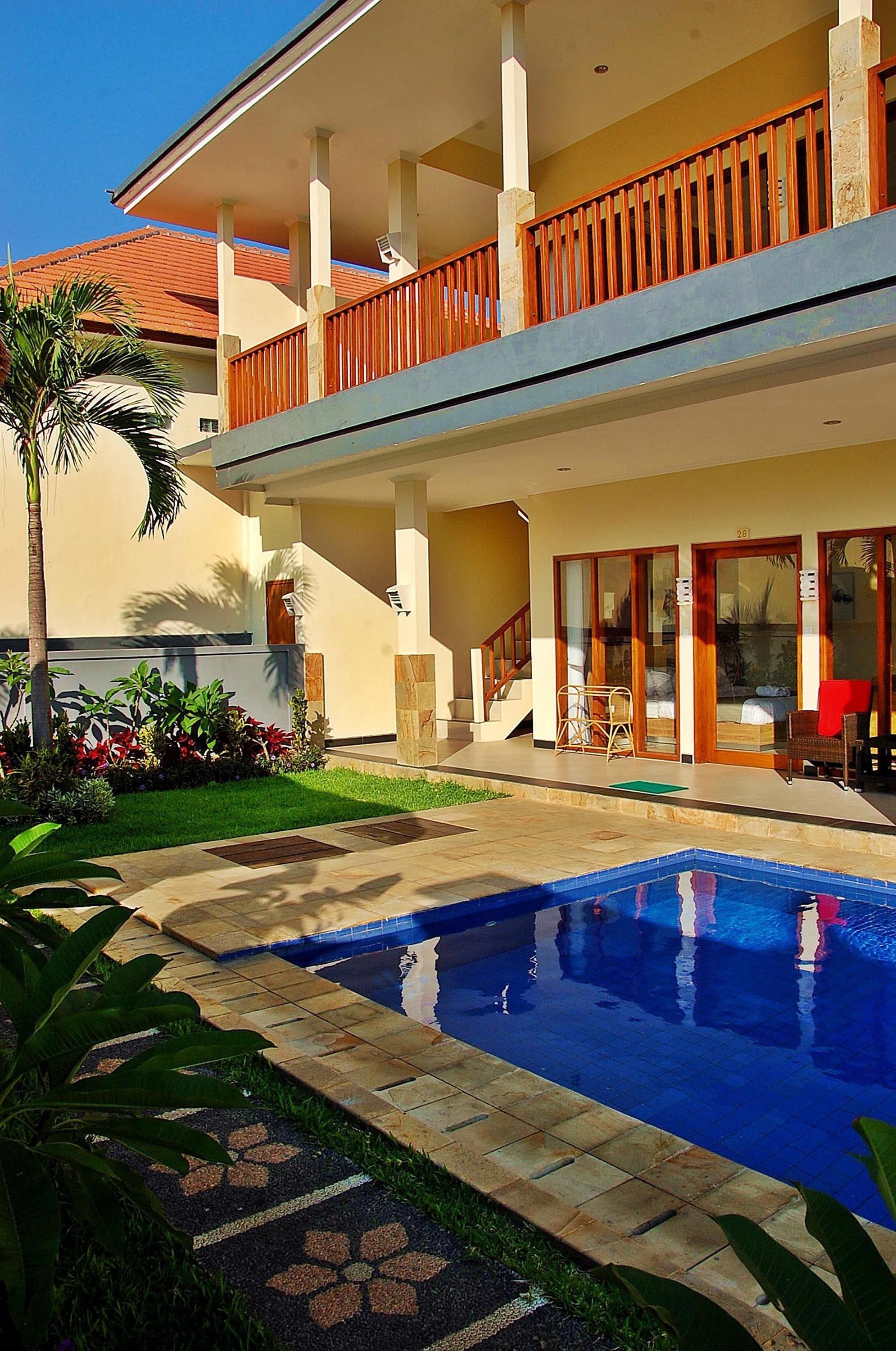 A two-story building with a swimming pool, a covered balcony, and a staircase leading to the upper floor.