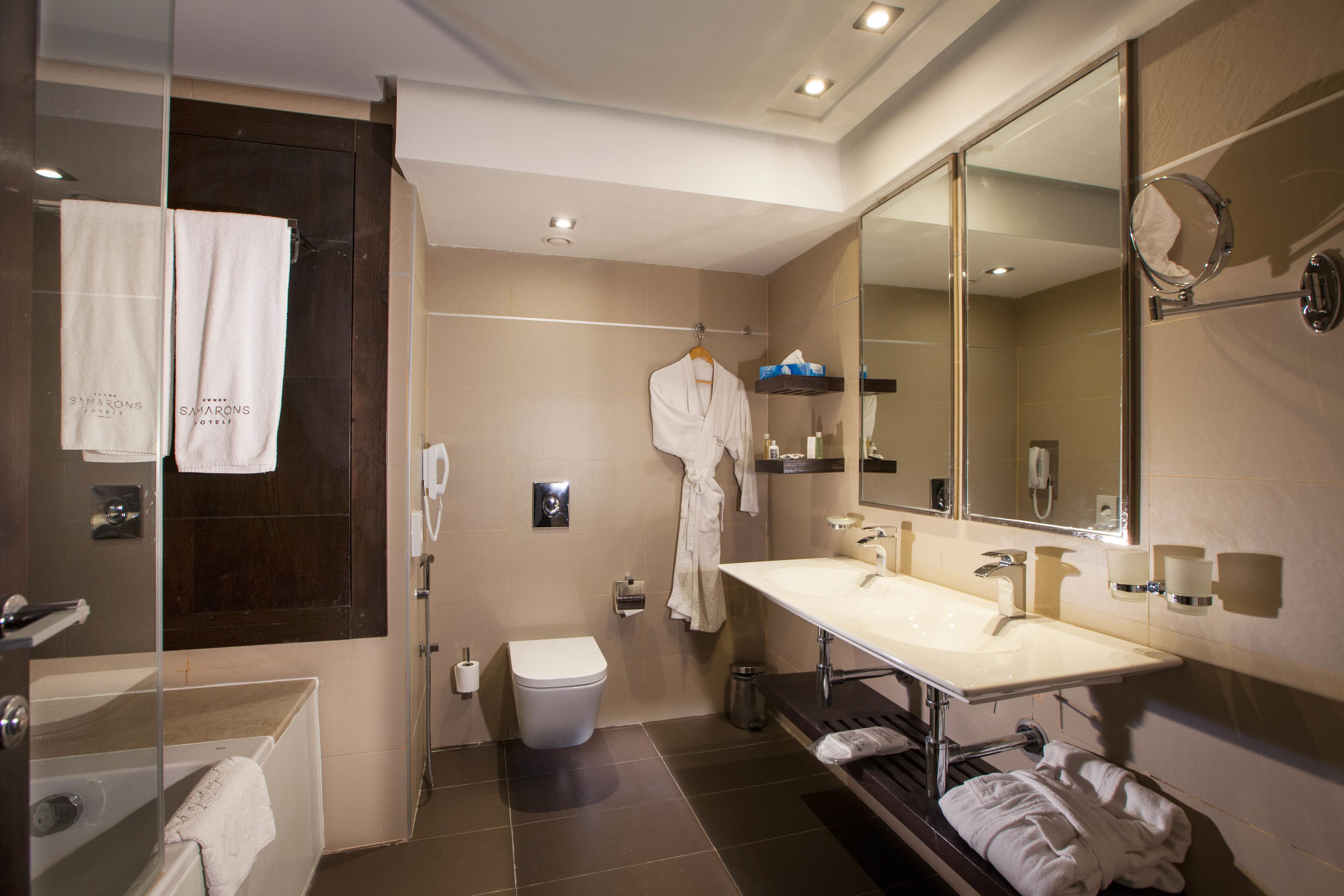 A modern bathroom with a large mirror, a bathtub, a toilet, and a vanity with a sink.