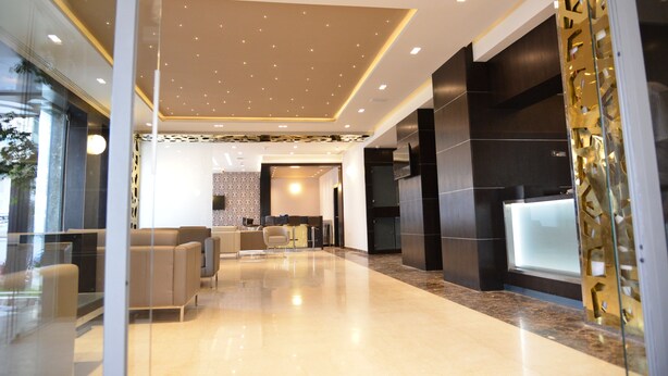 A modern lobby with a reception desk, seating area, and a glass partition. - Hôtel Samarons (Ariana)