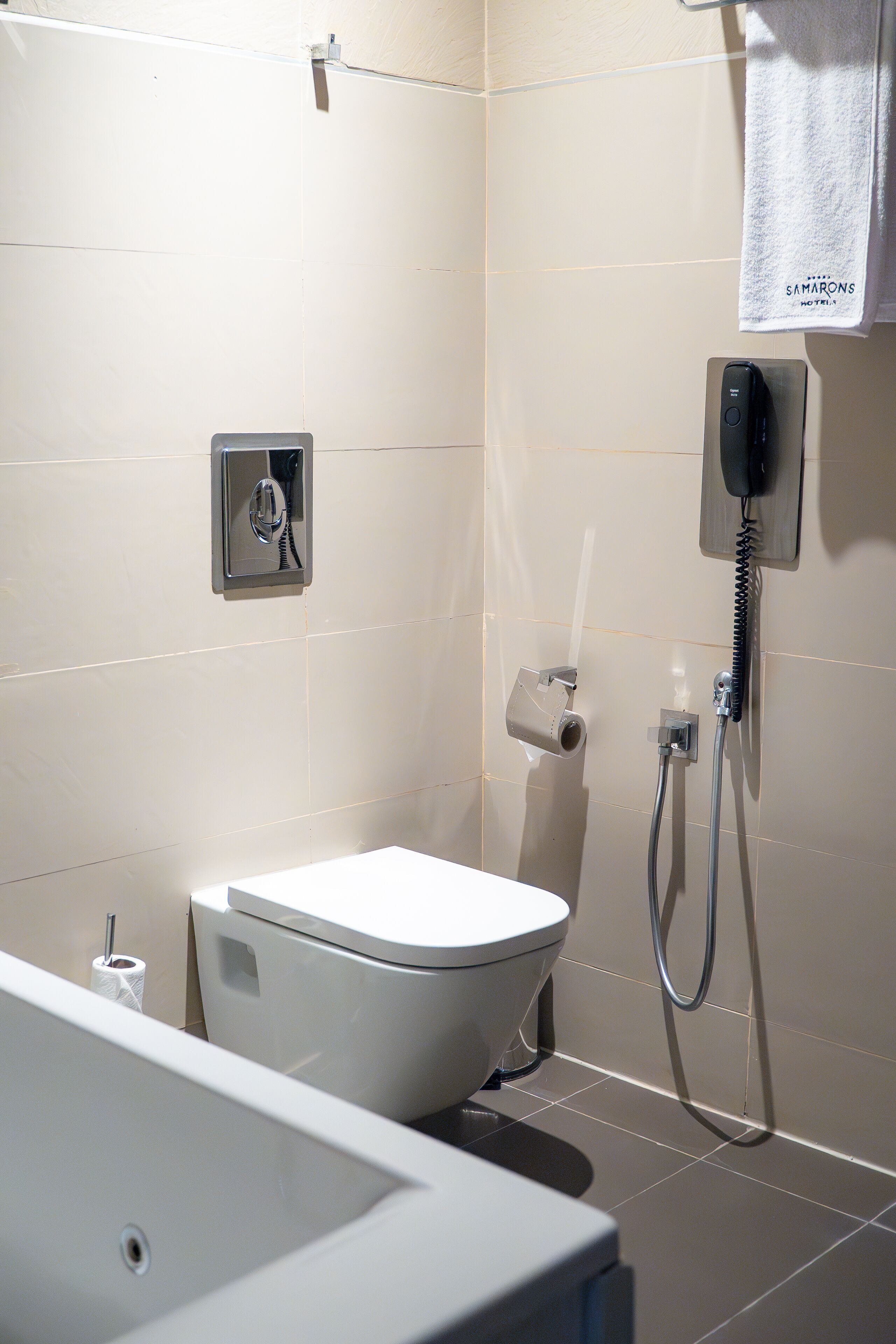 A bathroom with a toilet, bidet, and a towel hanging on a rack.