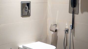 A bathroom with a toilet, bidet, and a towel hanging on a rack.