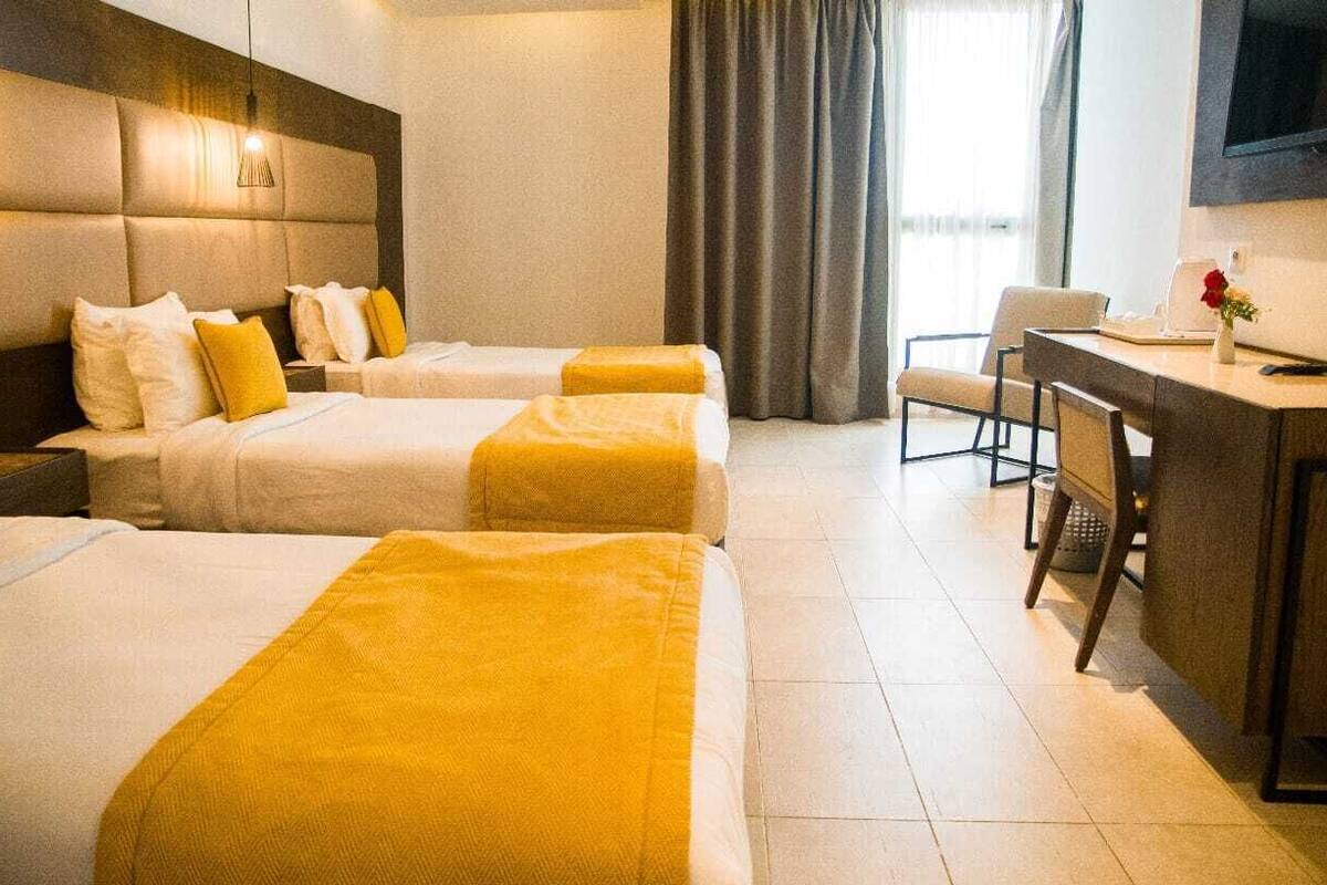 A hotel room with two beds, a desk, and a TV.