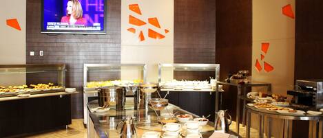 A buffet area with various food stations, a television screen, and modern decor.