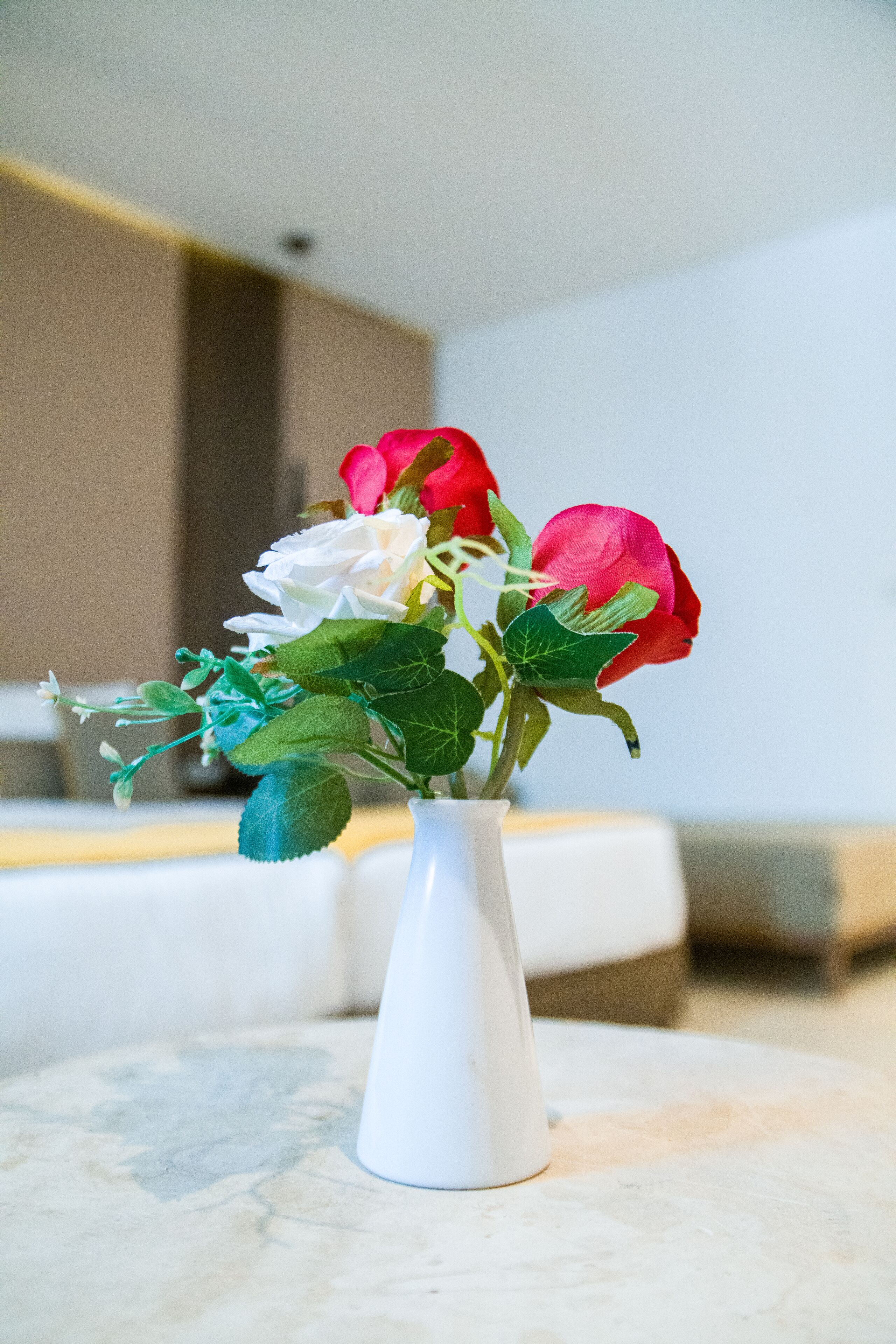 A white vase with a bouquet of roses on a marble surface.
