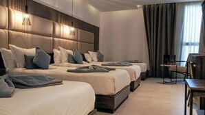 A hotel room with three beds, a desk, and a chair. - Hôtel Samarons (Ariana)