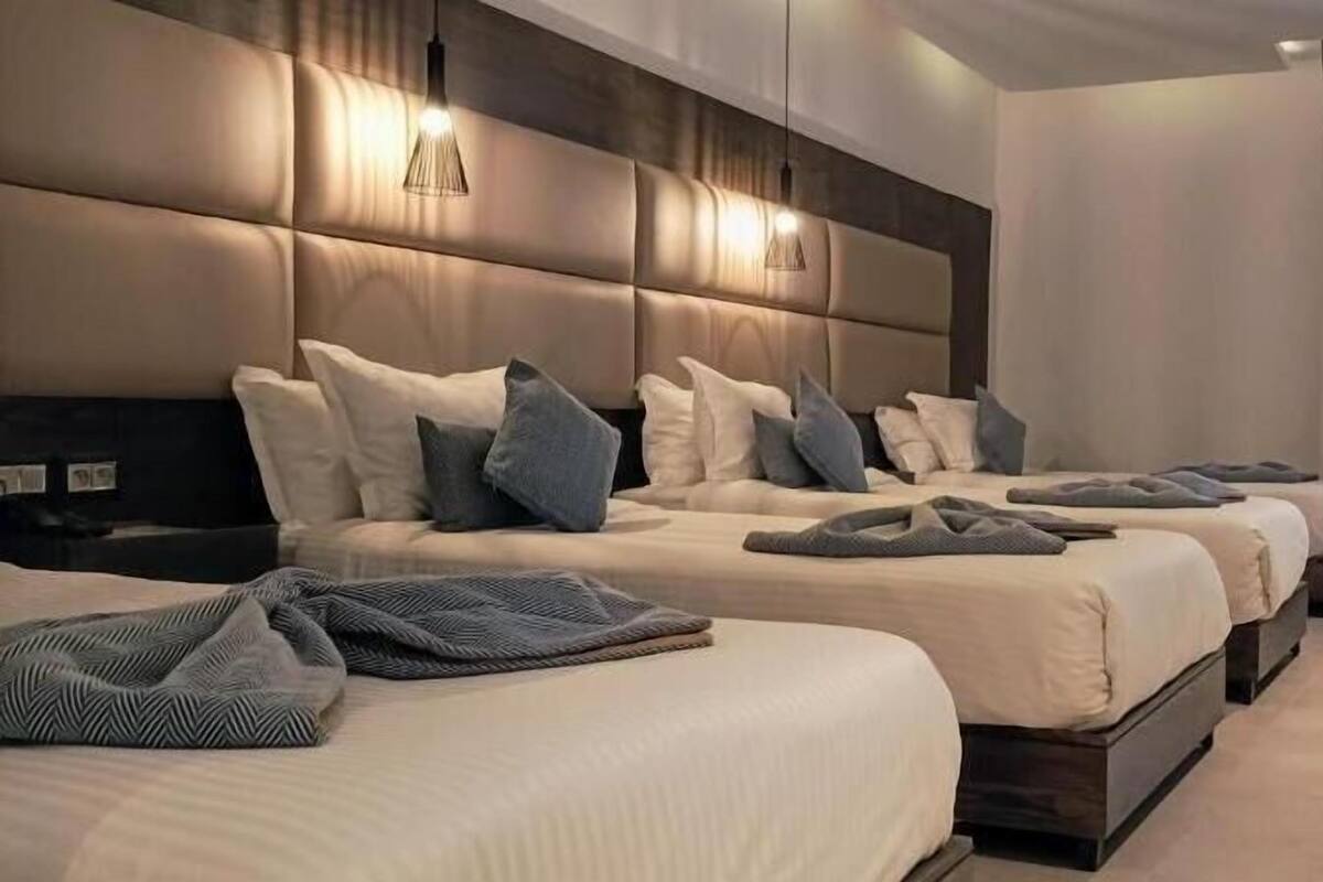 A hotel room with three beds, a desk, and a chair.
